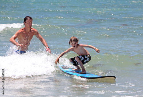 father teaching his young son how to surf