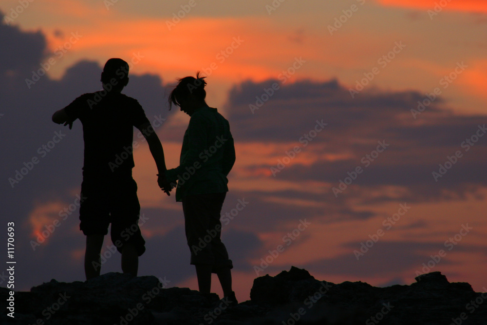 silhouette of couple walking in front of sunset
