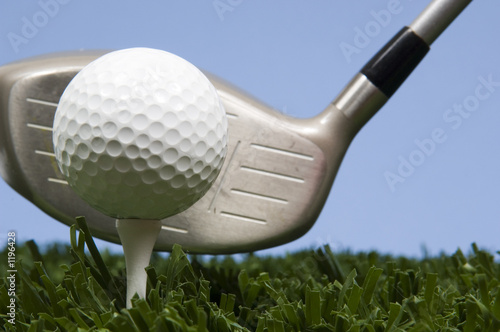 golf ball on tee on grass with driver