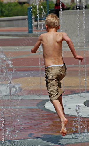 boy running and jumping through a fountain photo