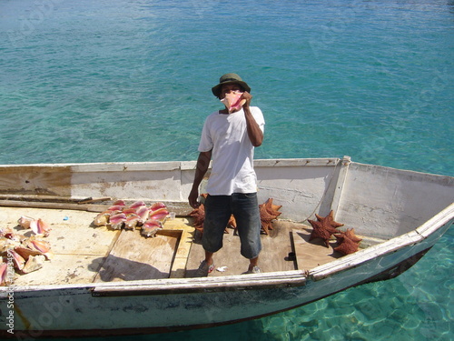 man selling conch shells in boat in nassau, bahama