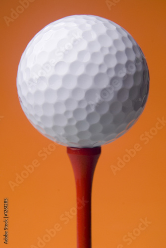 golf ball on red tee, orange background