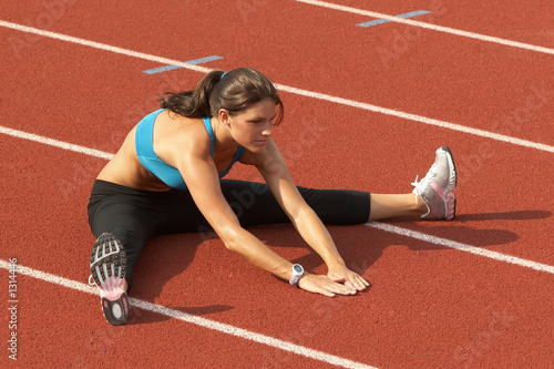 woman in sports bra stretching legs on track