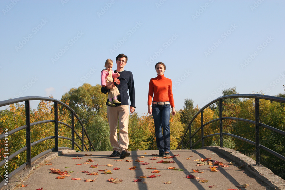 family with baby on autumn bridge