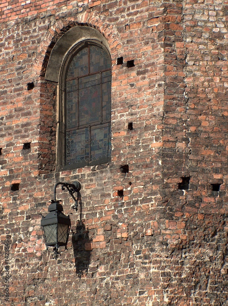 a brass lantern attached to a brick medieval wall