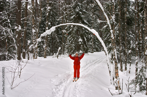 winter forest. woman skier smiling with hands up