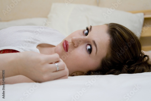 glamorous young woman lying on bed