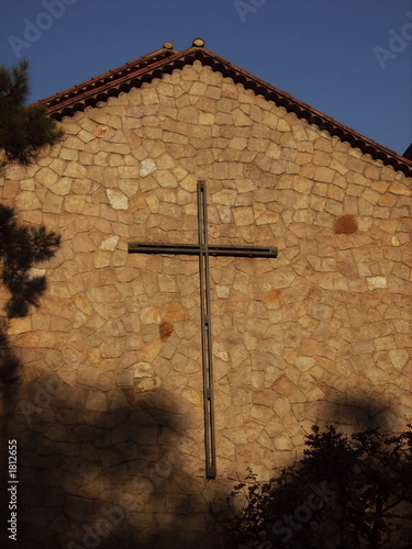old stone church with crucifix and blue sky photo