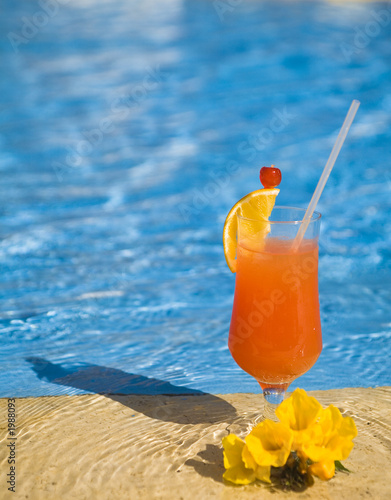 Sticker orange cocktail stands on edge of pool.