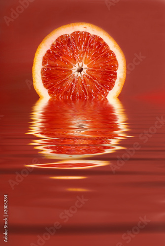 juicy half of a blood orange in water on a red background