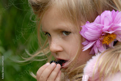 the little girl eats a blackberry