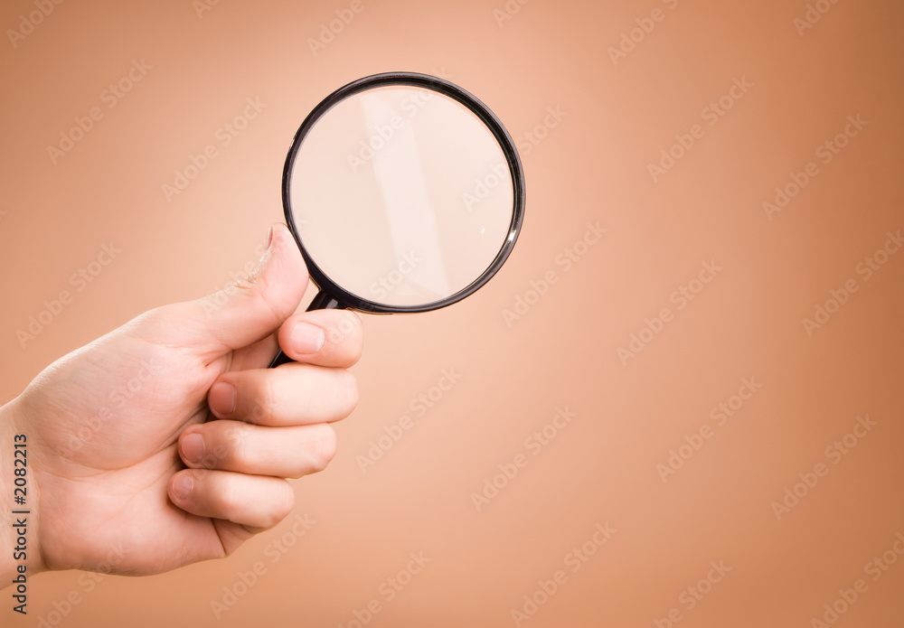hand holding magnifying glass on the beige backgro hand holding magnifying glass on the beige backgro