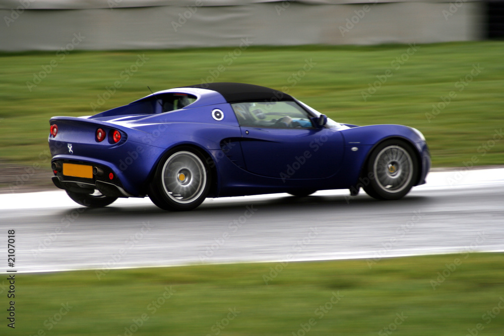 panning shot of a blue sports car on race circuit