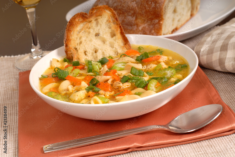 bowl of chicken noodle soup with rustic bread and a glass of win bowl of chicken noodle soup with rustic bread and a glass of win