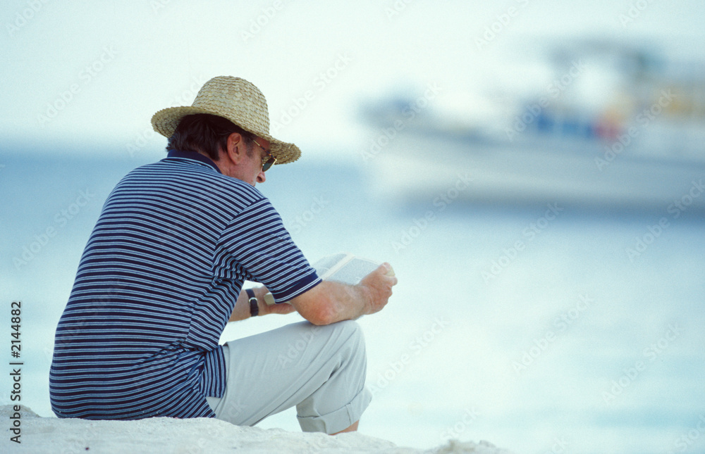 uomo legge sulla spiaggia