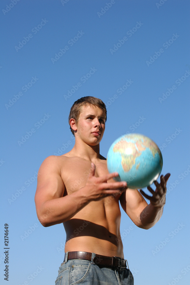 young muscular man playing with a terrestrial globe
