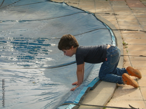 jeune garçon se penchant au dessus d'une piscine