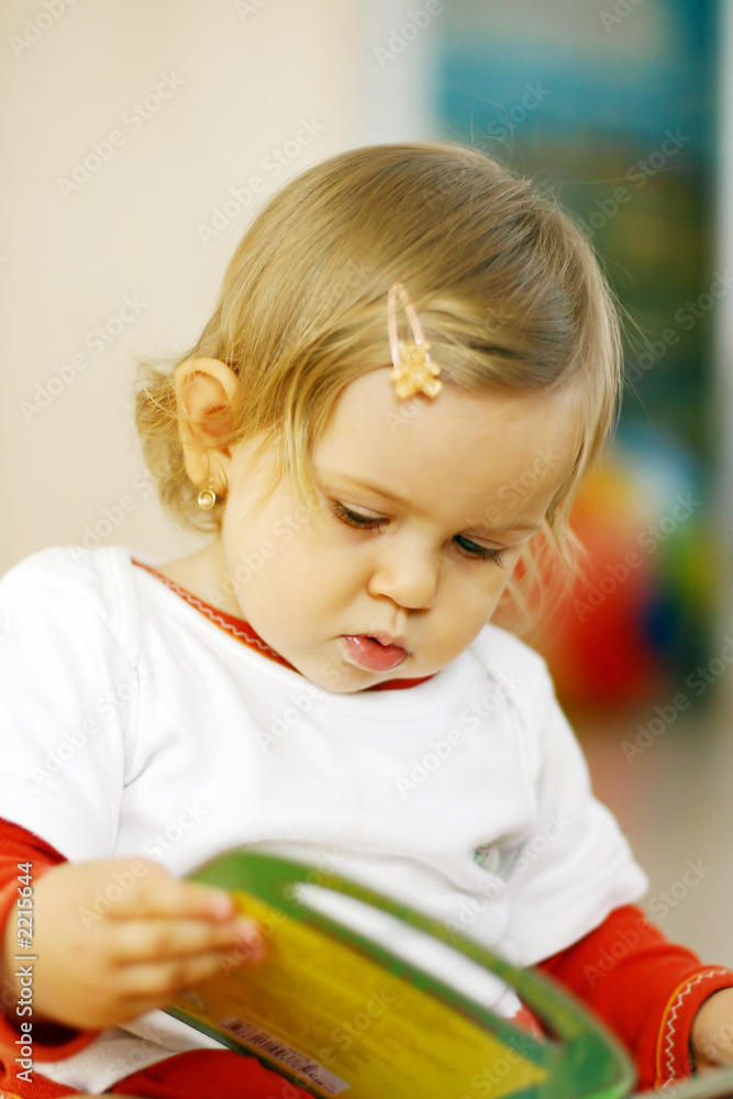 Fototapeta premium small baby reading a picture book