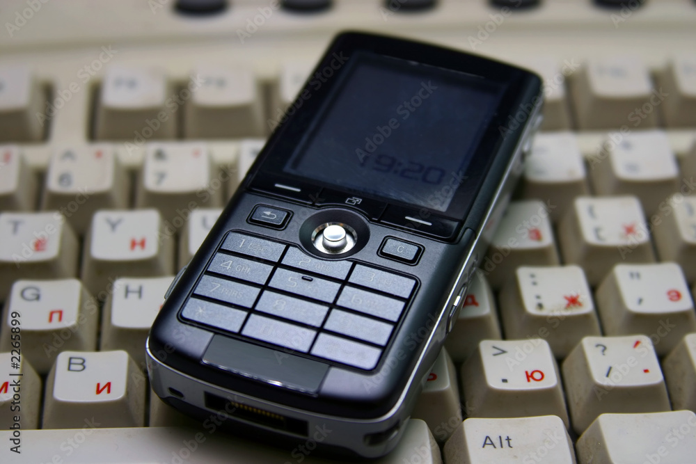 black mobile phone on a dirty keyboard. black mobile phone on a dirty keyboard.