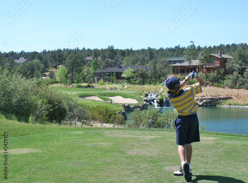 young golfer hitting a shot over a water hazard