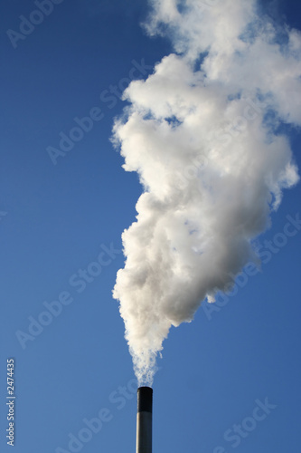 chimney billowing white smoke into blue sky