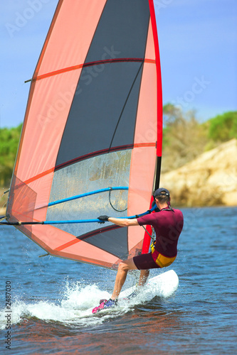 man in wetsuit on fastmoving windsurfer
