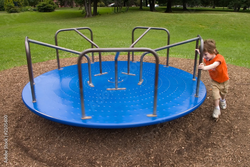 young boy pushes a merry-go-round