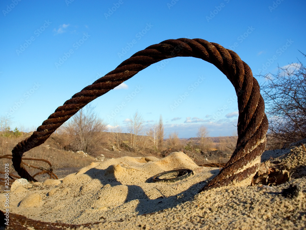 Fototapeta premium thick rusty wire rope and ring in sand