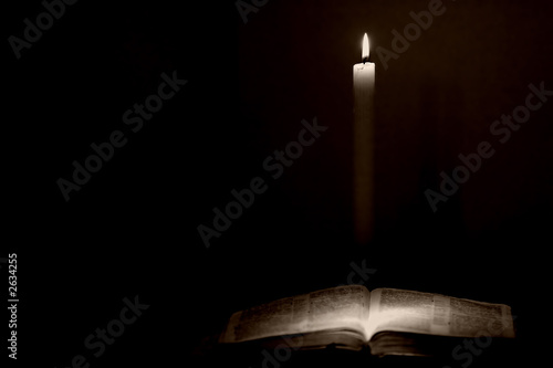 holy bible lit by a candle