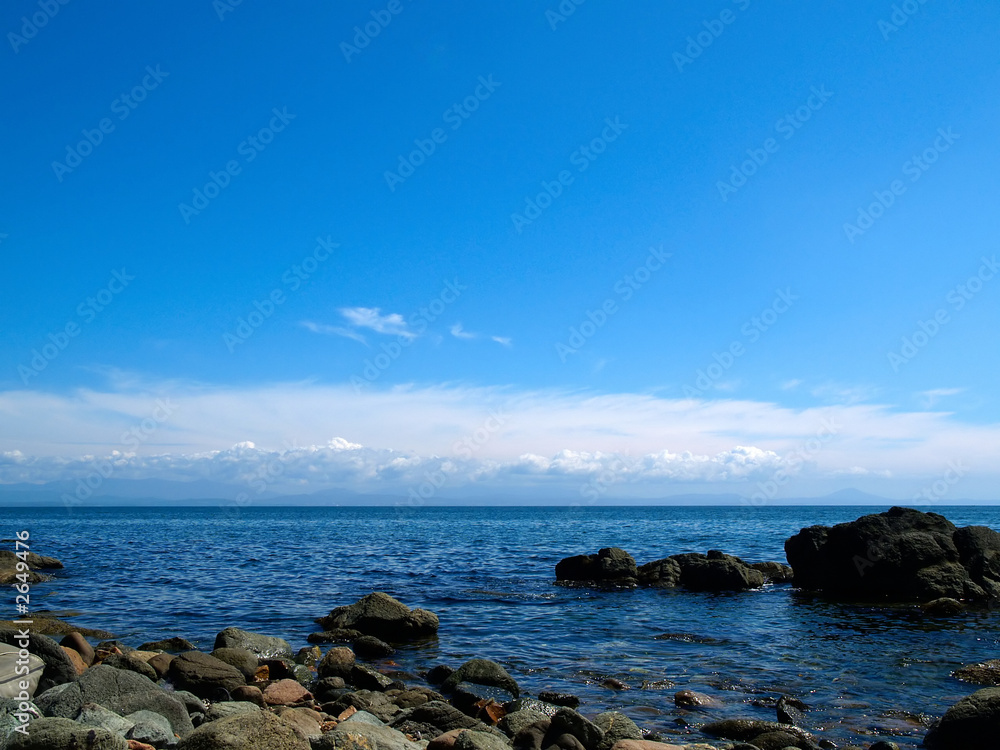 rocky coast of ocean with sky and clouds