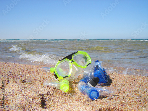 snorkel gear on a yellow sandy beach lying near upon coast