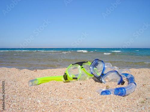 snorkel gear on a yellow sandy beach lying near upon coast