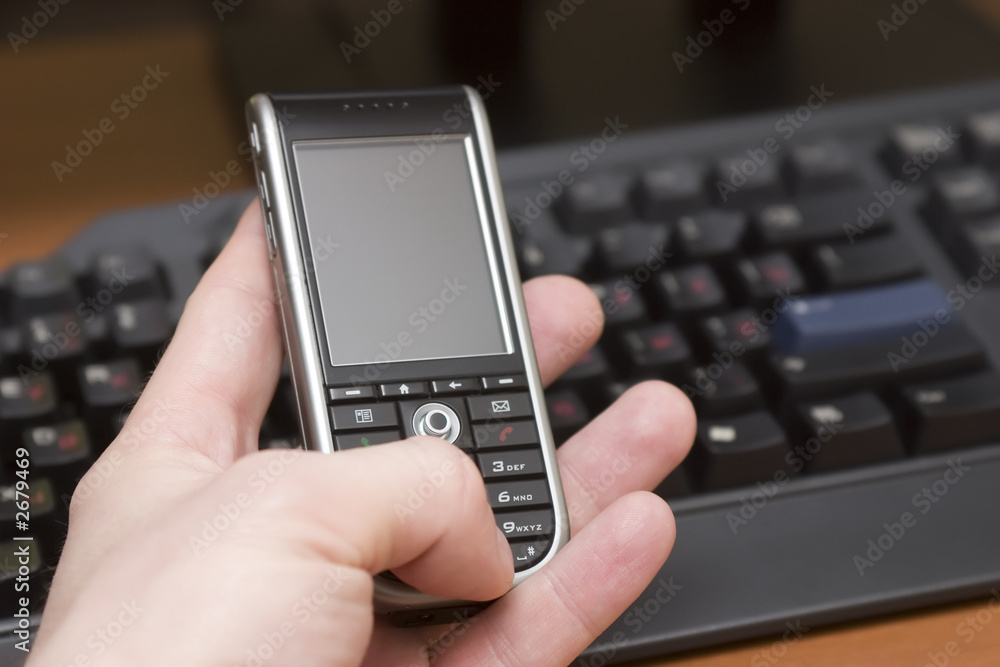 cellular phone in hand of a man on a workplace cellular phone in hand of a man on a workplace