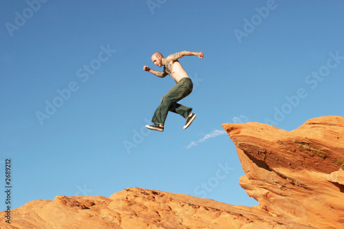 man jumping on red rocks