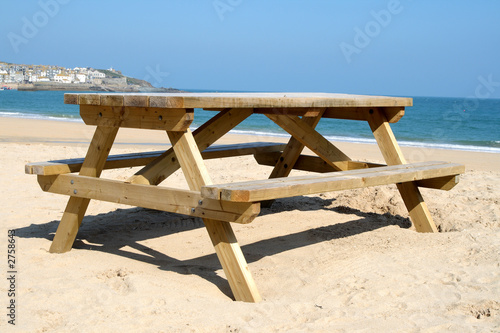 a wooden picnic table on the beach in st. ives, co