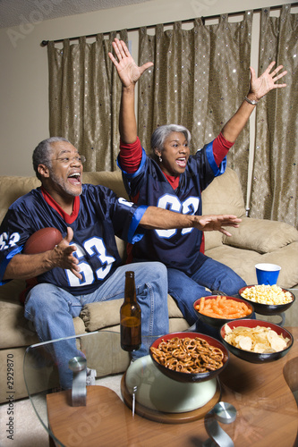middle-aged african-american couple watching sports on tv.