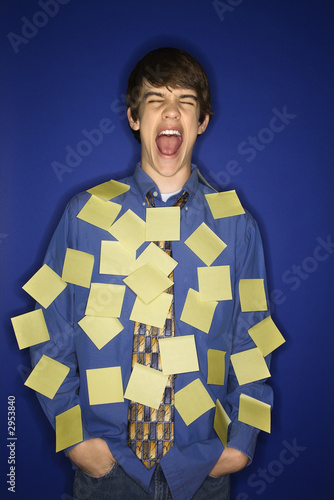 caucasian teen boy covered with sticky notes screaming.