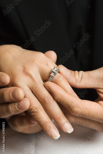 Adult male putting ring on female's hand.
