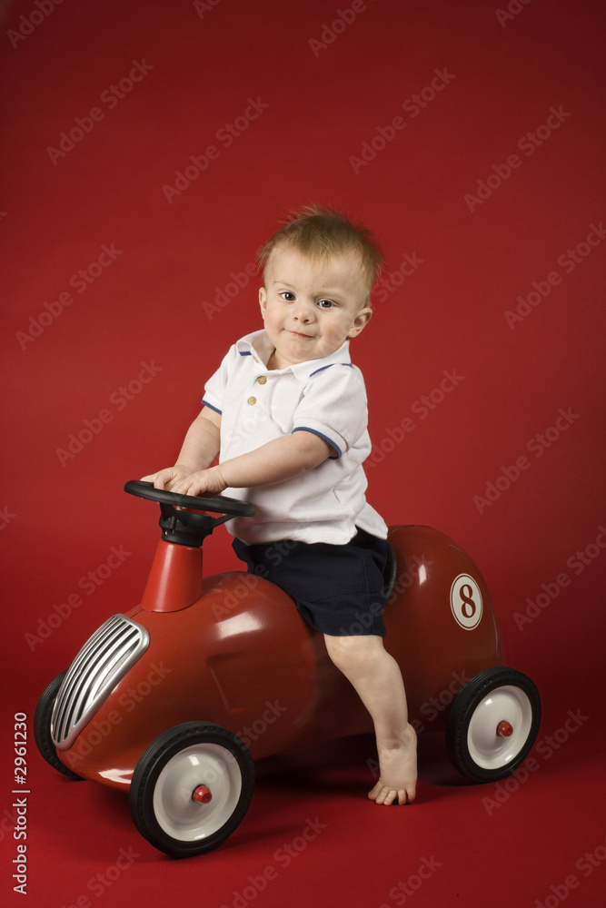 Baby boy sitting on play car. Baby boy sitting on play car.