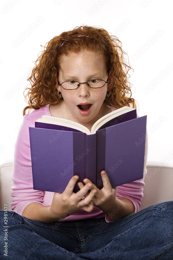 Girl sitting reading book looking surprised. Girl sitting reading book looking surprised.