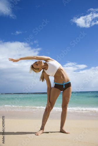 Woman stretching on beach.