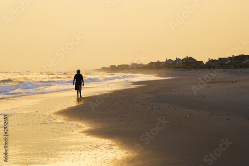 Boy walking on beach at sunset