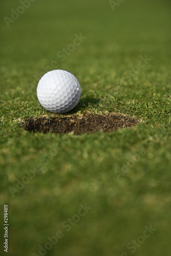 Golf ball close to edge of cup.