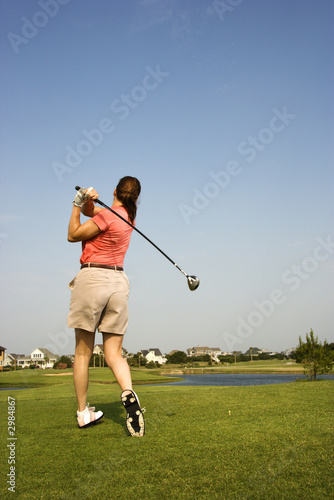 Woman swinging golf club.