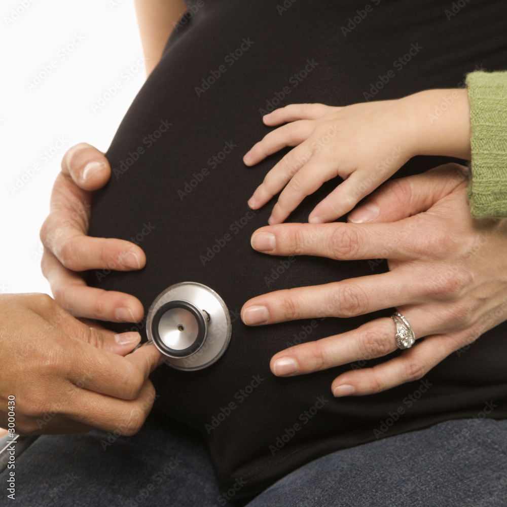 nurse holding stethoscope on pregnant belly.