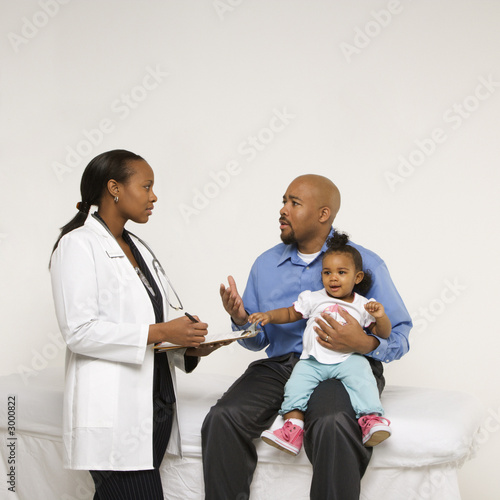 father holding baby talking to pediatrician.