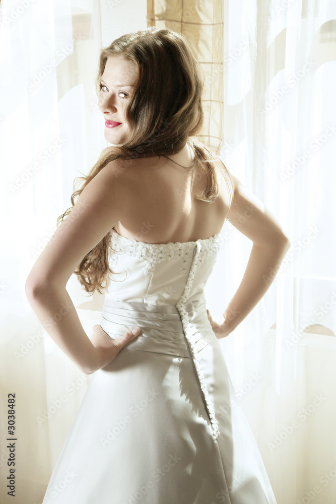 Beautiful smiling young bride at window in natural light Beautiful smiling young bride at window in natural light