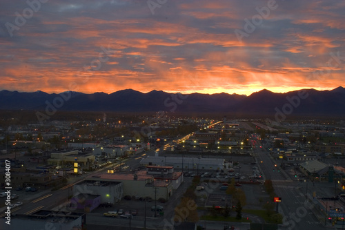 Sunrise over Anchorage Alaska with the town and a few cars in the foreground and colorful sky with clouds behind photo