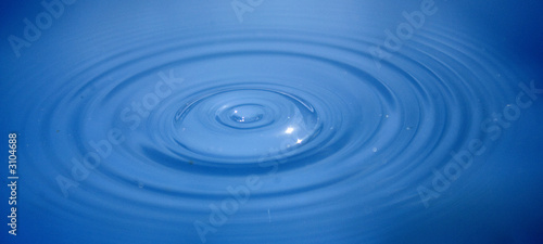 Ripples across blue water seconds after a drop has hit the surface