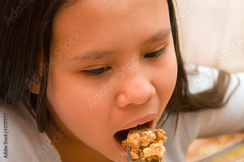 young girl eating cake from fork